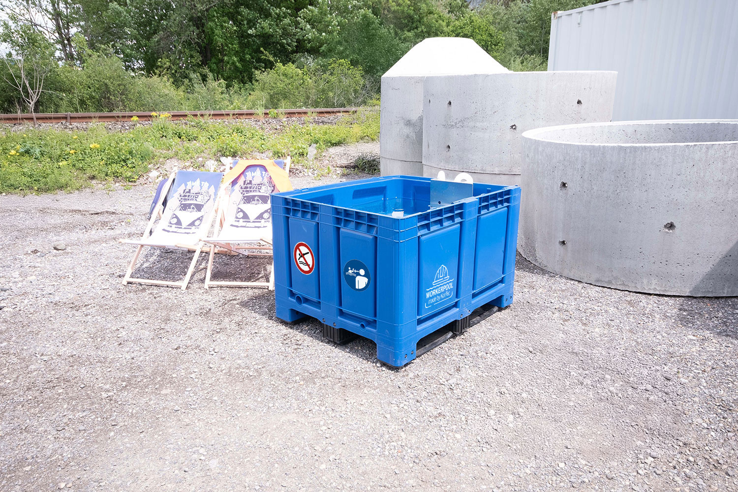 Blaue Bigbox des Workerpools im Außenbereich auf Schotterfläche mit weißem Logo und Sicherheitsaufklebern