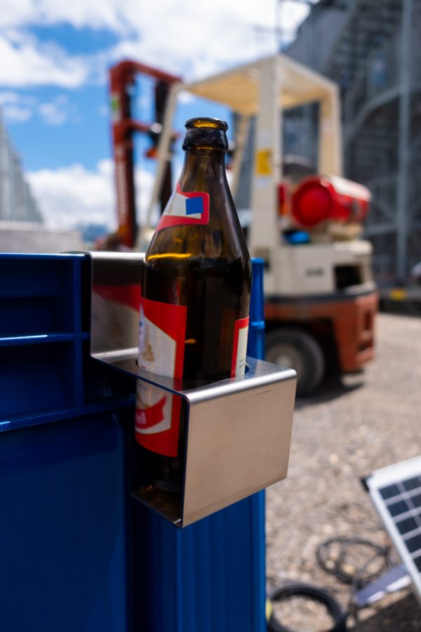 Flaschenhalter aus Metall mit eingesetzter Trinkflasche an einem Workerpool-Arbeitsplatz.