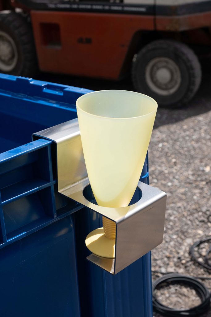 Flaschenhalter aus Metall mit eingesetztem Kunststoffbecher an einem Workerpool-Arbeitsplatz.